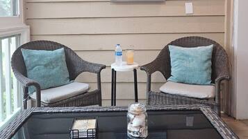 Une pièce avec des chaises en osier, une table en verre, un tableau représentant un oiseau et une pancarte sur laquelle on peut lire : « La vie est belle à la plage ».