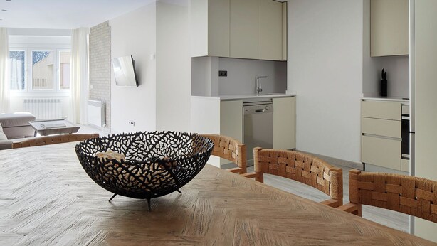 A modern kitchen with a built-in dishwasher, a dining area with a wooden table and woven chairs, and a large window providing natural light. - Marcatosa by FeelFree Rentals (Baqueira)