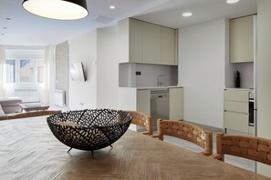 Una cocina moderna con lavavajillas incorporado, una zona de comedor con mesa de madera y sillas tejidas, y un amplio ventanal que proporciona luz natural.