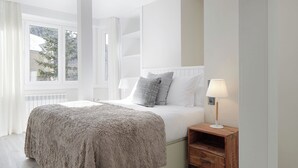 A bedroom with a bed, a bedside table with a lamp, and a window with curtains. - Marcatosa by FeelFree Rentals (Baqueira)
