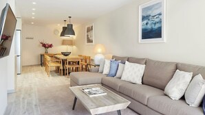 A modern living room with a beige sofa, a wooden coffee table, and a dining area with a wooden table and chairs. - Marcatosa by FeelFree Rentals (Baqueira)