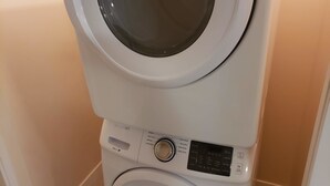 Ein übereinander angeordneter Wasch- und Trockner mit Bedienfeld, das verschiedene Einstellungen und eine Start-/Stopp-Taste bietet.