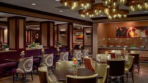 Un restaurante con mesas y sillas redondas, una zona de bar y decoración en las paredes.