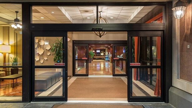 Una entrada de hotel con diseño moderno, que incluye una zona de recepción y un área de descanso con sofás, así como un candelabro.