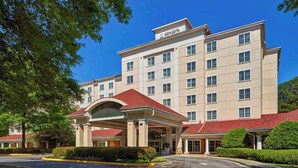 Un hotel con entrada principal, varios pisos y un cielo azul despejado.