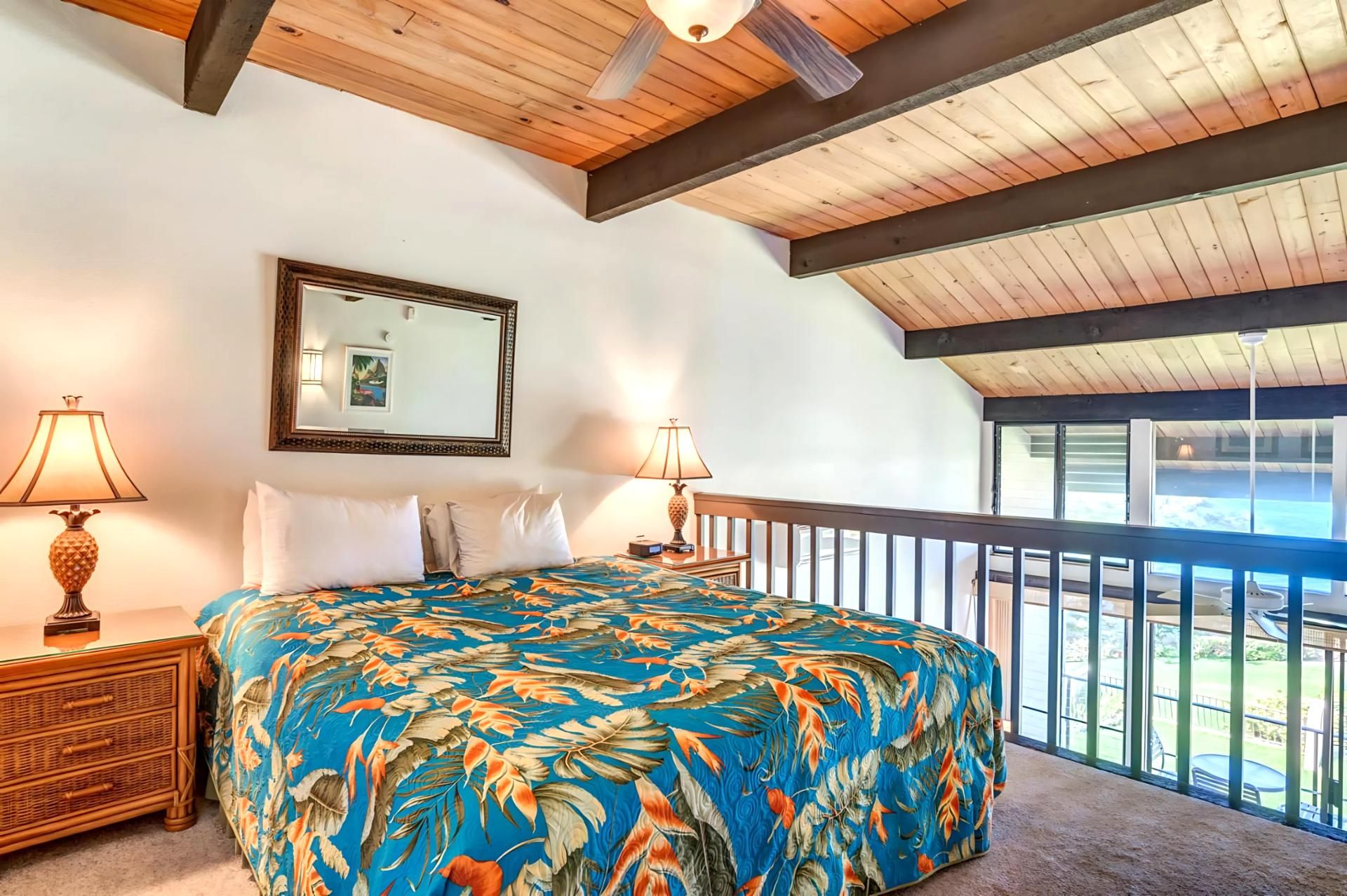 A bedroom with a bed, two nightstands, a mirror, and a balcony with a view.