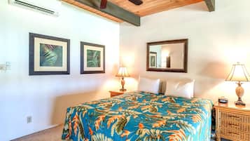 A bedroom with a bed, two wall-mounted picture frames, a ceiling fan, and a bedside table with a lamp.