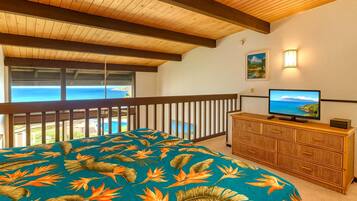 Un dormitorio con cama, televisión y vista al océano.