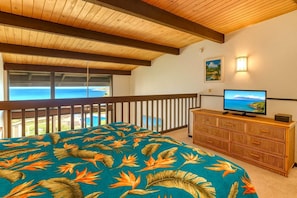 Una camera da letto con un letto, una televisione, un comò e un balcone vista mare.