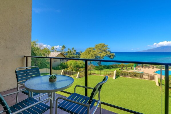 Ein Balkon mit Tisch und Stühlen, ein kleiner Pool und Blick auf das Meer und Grünflächen.