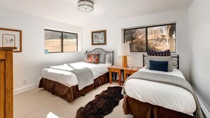 Un dormitorio con dos camas, una ventana, una lámpara y una alfombra.