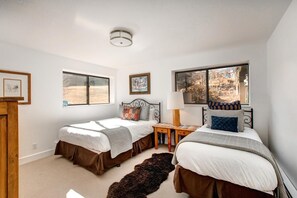 Un dormitorio con dos camas, una ventana, una lámpara y una alfombra.