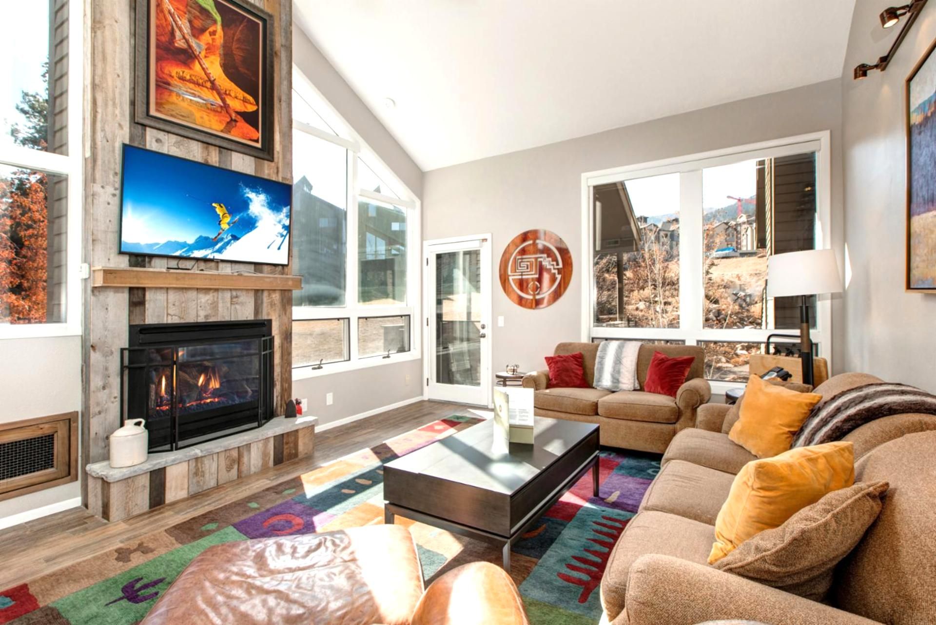 A living room with a fireplace, a large TV, and a sofa with cushions.