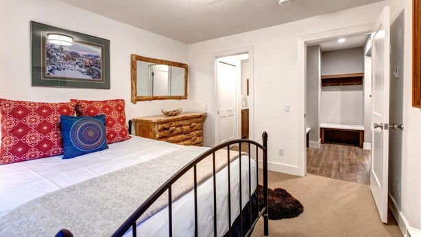 A bedroom with a bed, a dresser, a mirror, and a door leading to a bathroom.
