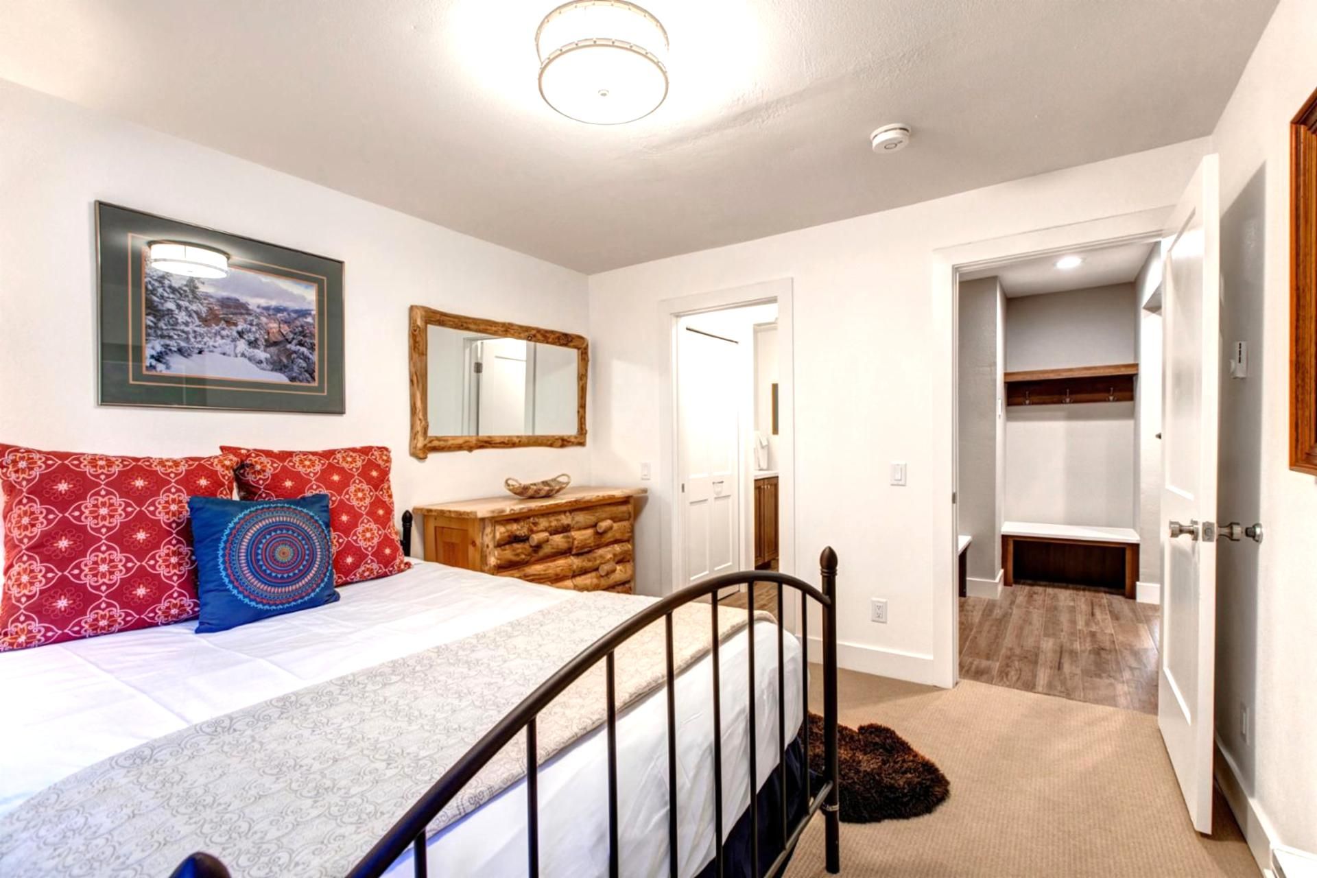 Une chambre à coucher avec un lit, une commode, un miroir et un placard.