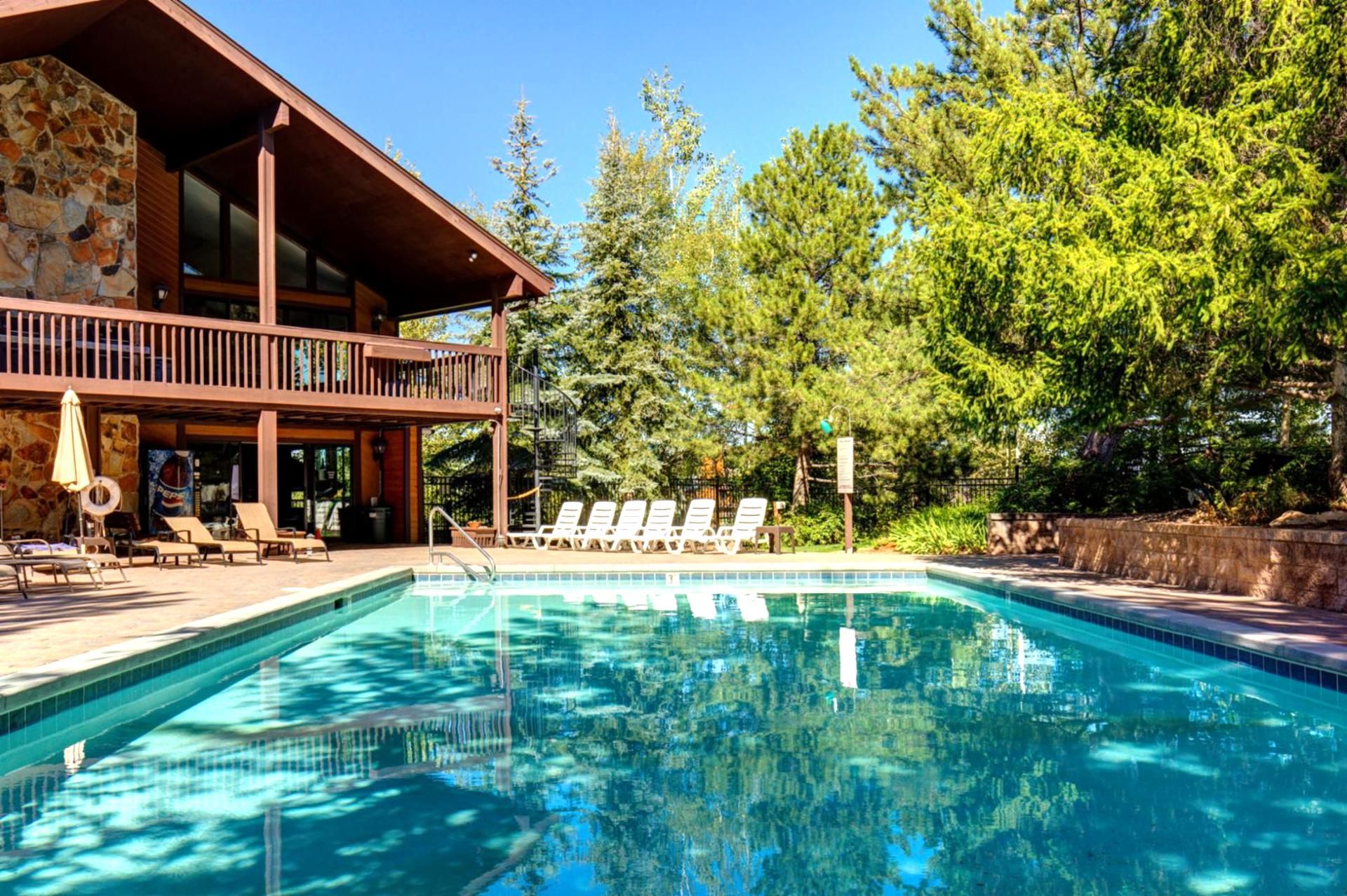 Un espace piscine avec des chaises longues et une terrasse en bois.