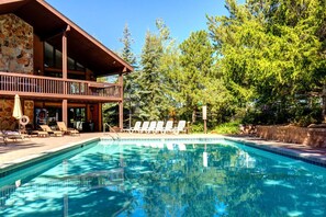Un área de piscina con sillones de descanso y una terraza de madera.