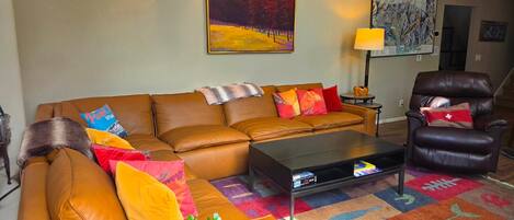 Una sala de estar con sofá, sillón, mesa de centro y alfombra colorida.