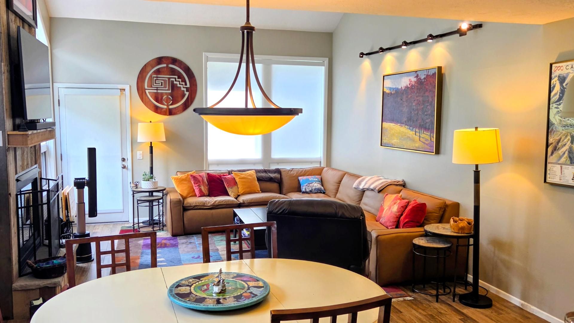 A modern living room with a round dining table, a sofa, and a large window.