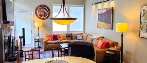 A modern living room with a round dining table, a sofa, and a large window.