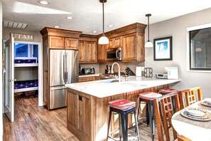A kitchen with wooden cabinets, stainless steel appliances, a large island, and bar stools.
