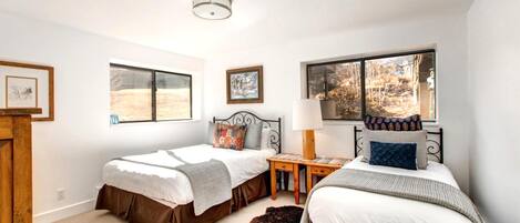 A bedroom with two beds, a wooden nightstand, a lamp, and a rug.