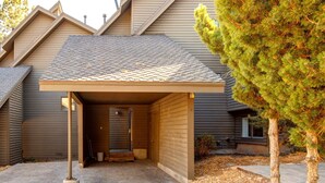 A covered garage entrance with a concrete foundation, a wooden door, and a small step leading up to it.