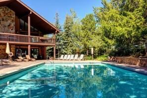 Una piscina con sillas de descanso y una terraza de madera.