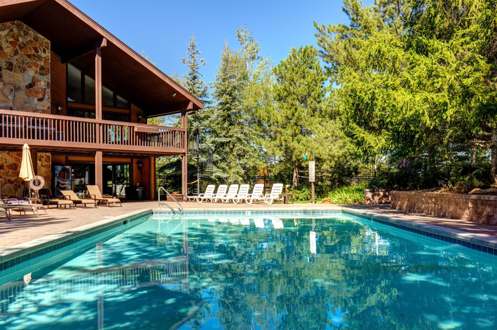 A swimming pool with lounge chairs and a wooden deck.