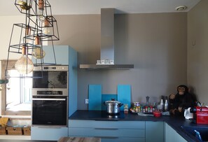 Enjoy cooking in this stylish kitchen with a coffee machine and kettle, featuring a unique light fixture above the stove.