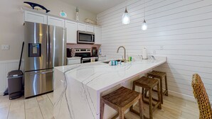 Una cocina moderna con una isla grande, electrodomésticos de acero inoxidable y taburetes de madera.