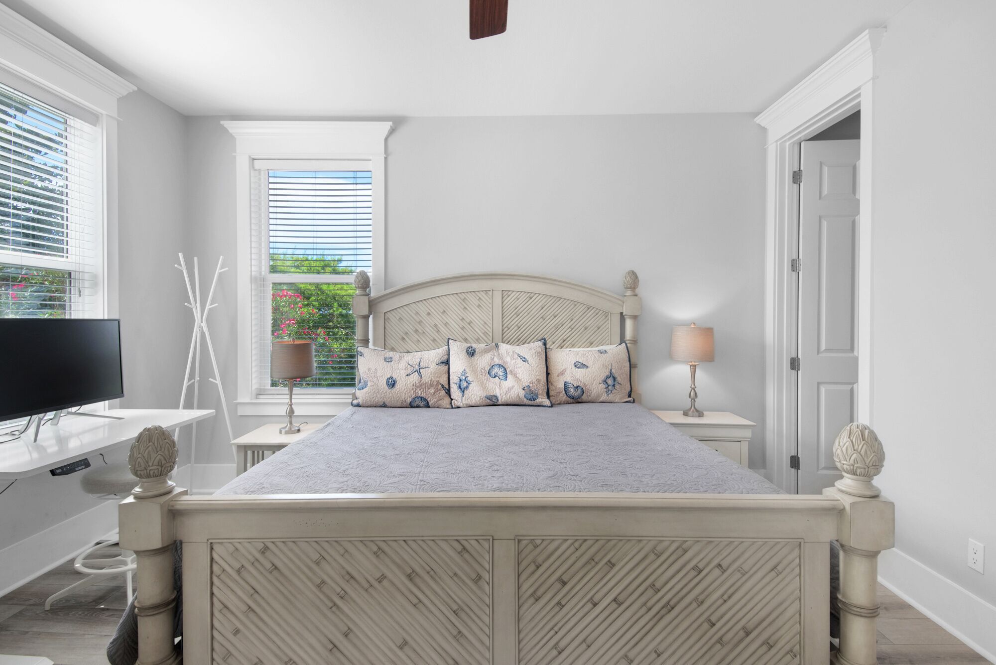 A bedroom with a bed, a TV, a window with blinds, a lamp, and a door.