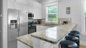 A modern kitchen with white cabinetry, stainless steel appliances, a granite countertop, and a window with a view of greenery. - Townhome-Comm Pool-Private Beach Access 5 Min Walk (Miramar Beach)