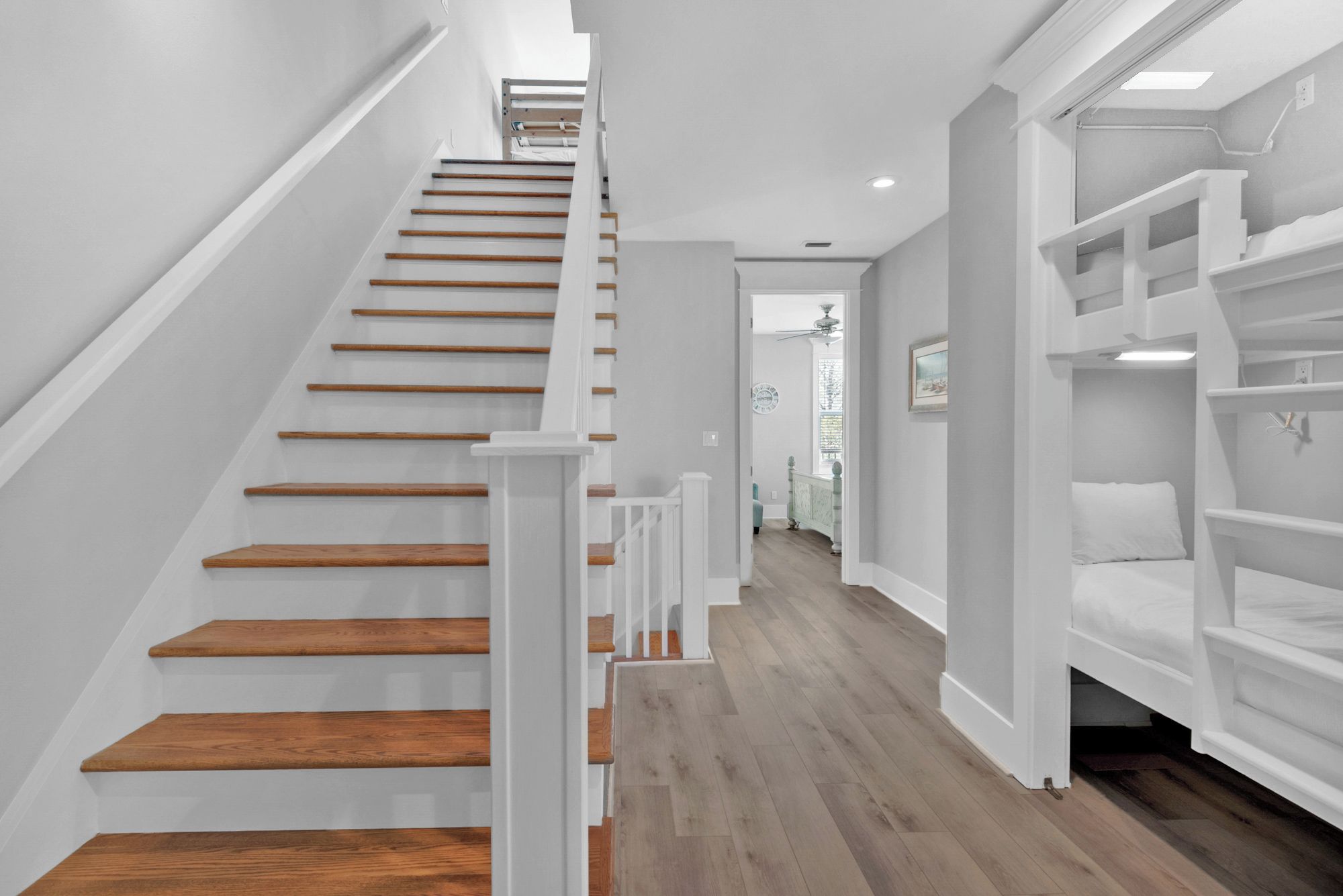 A staircase with wooden steps and white railings leading to a landing.