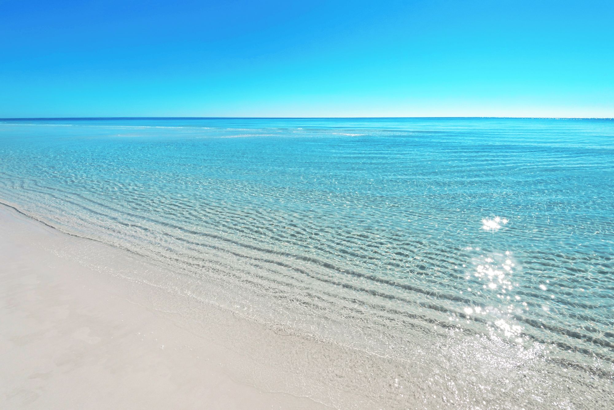 A beach with clear water and a sandy shore.