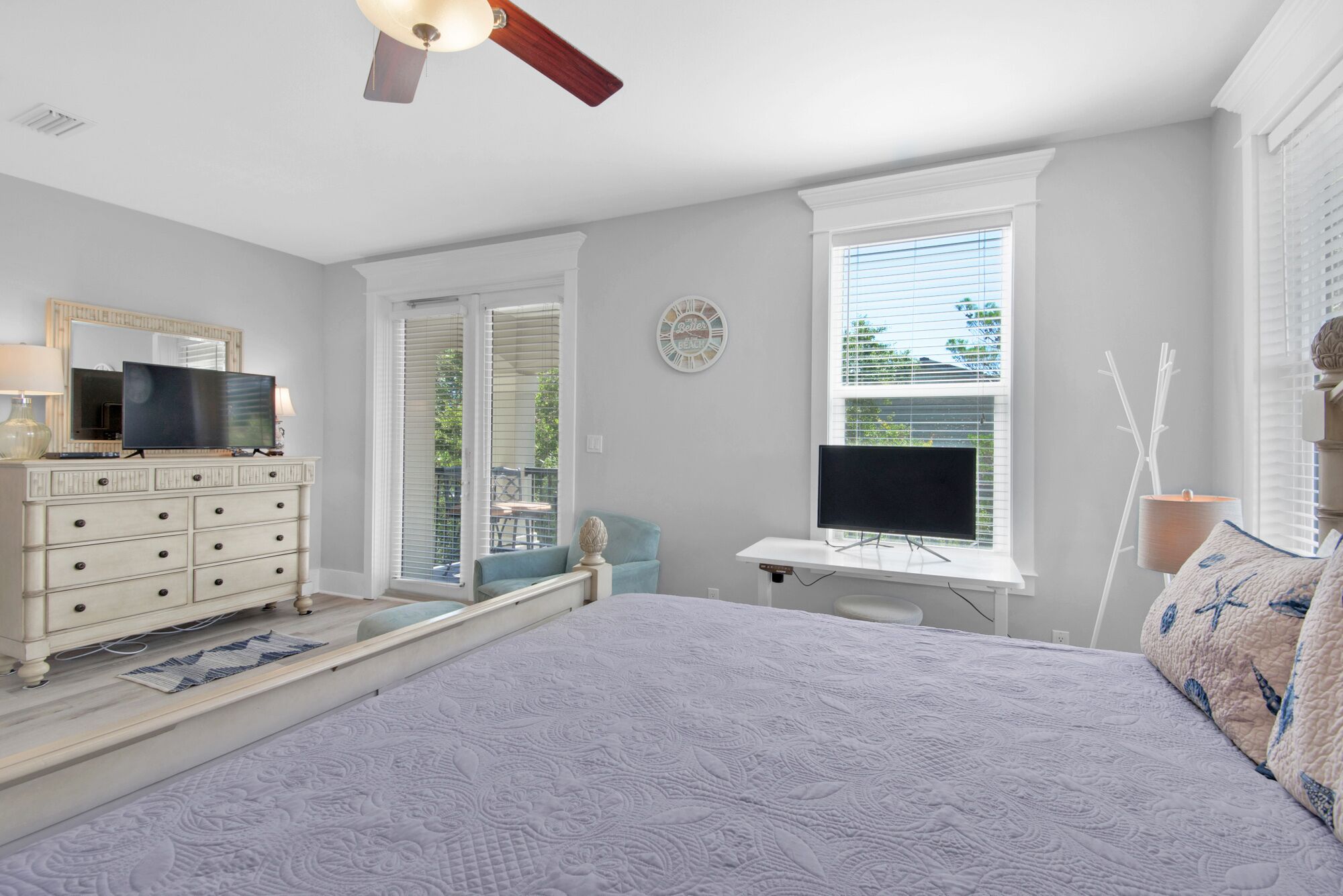 A bedroom with a bed, dresser, TV, and a desk with a computer.