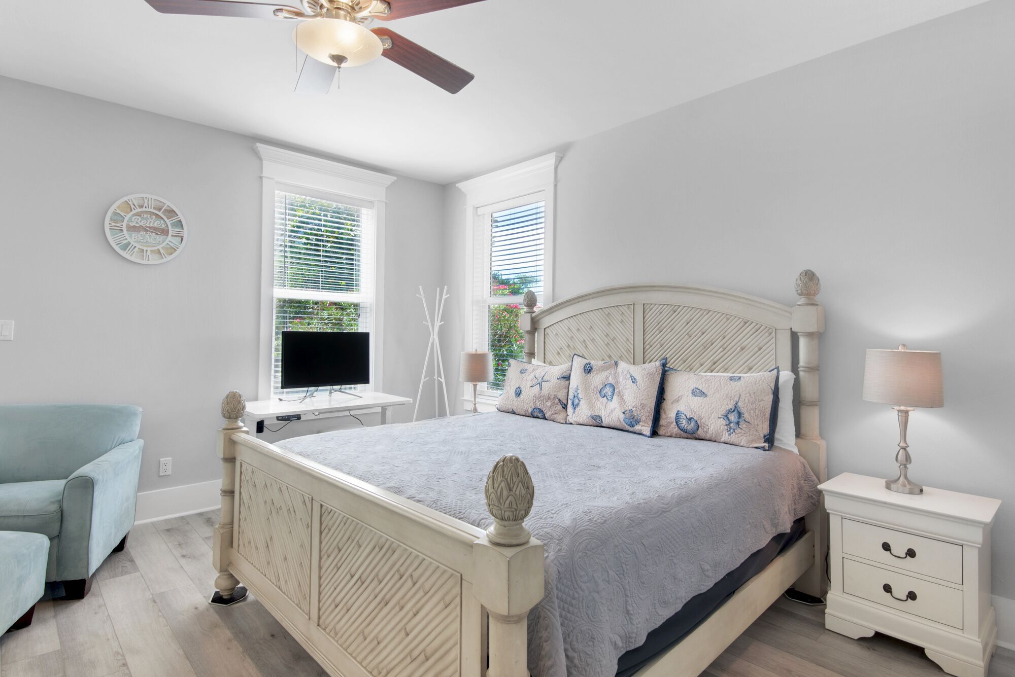 Une chambre à coucher comprenant un lit, une table de chevet, une chaise, un téléviseur et un ventilateur de plafond.