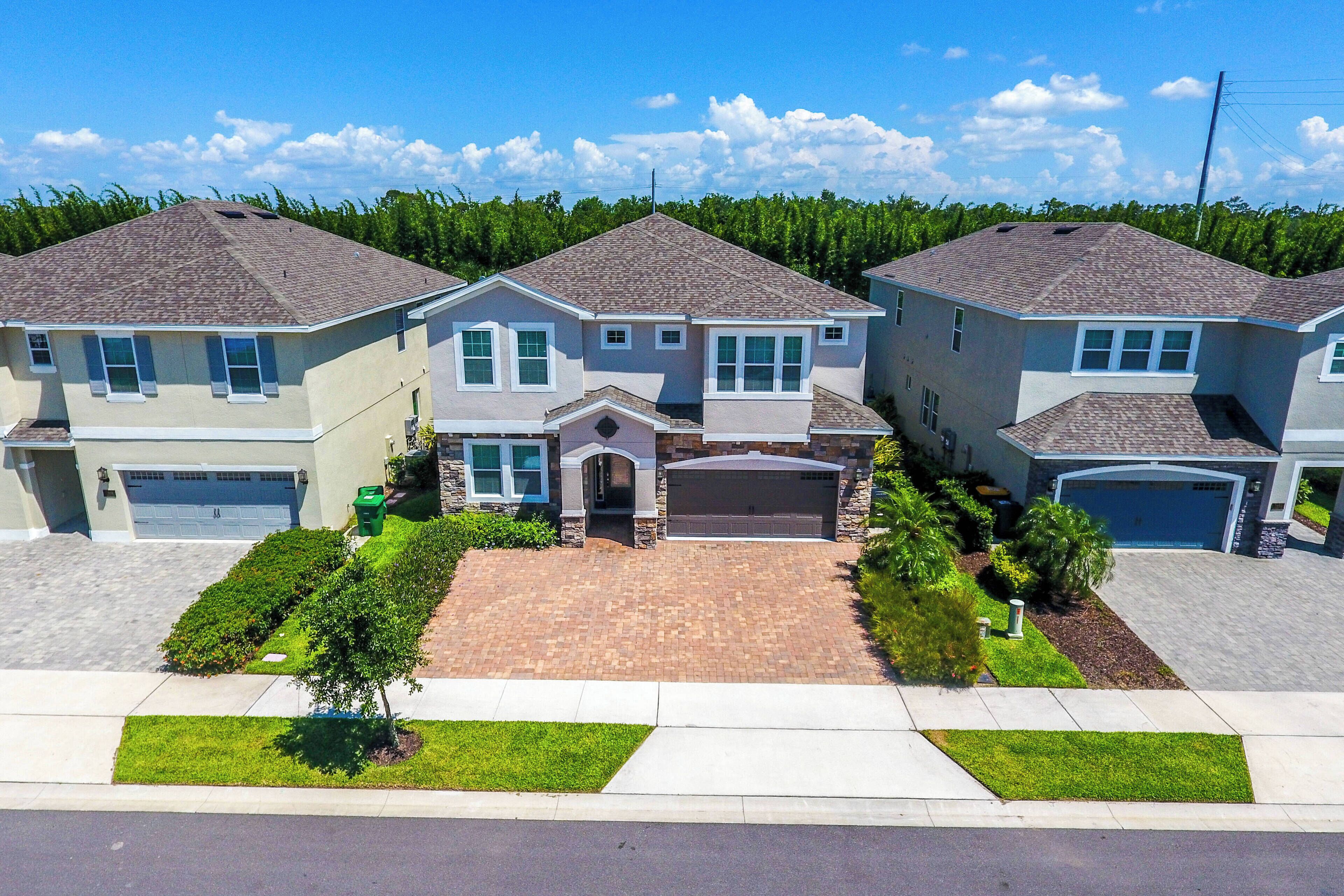 A suburban neighborhood with three two-story houses, each with a garage, driveway, and well-maintained lawns.