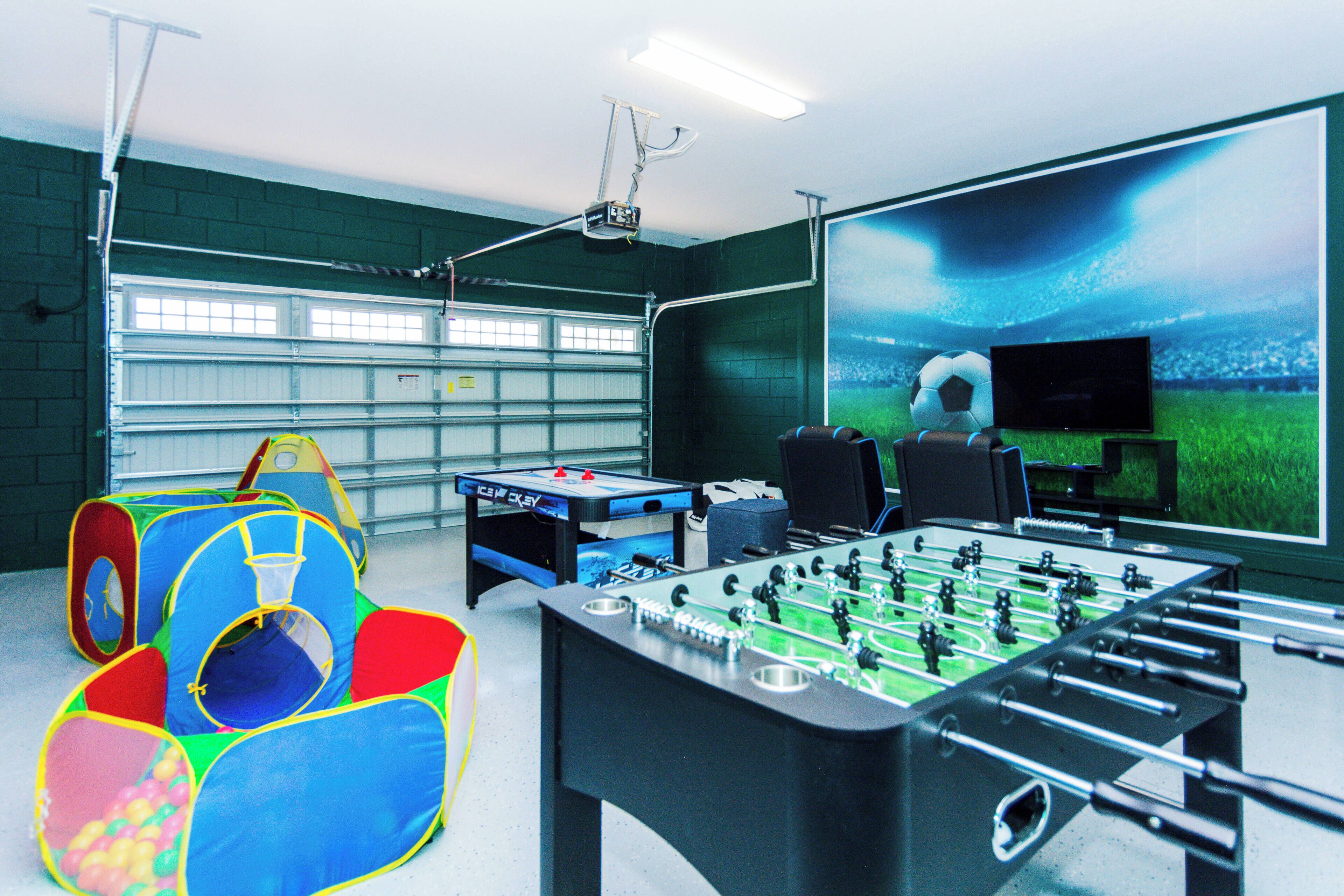 Une pièce équipée d’un baby-foot, d’un écran de projection et d’un espace de jeux avec une piscine à balles.