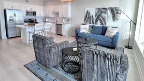 Un salon moderne avec un canapé bleu, un pouf à rayures et une table basse.