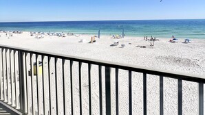 Une plage avec un ciel dégagé, un rivage sablonneux et une rambarde au premier plan.