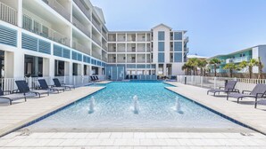 Un hôtel doté d’une piscine, de plusieurs balcons et offrant une vue sur un ciel dégagé.