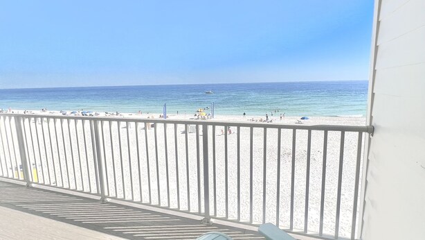 Une terrasse en bois offrant une vue sur une plage et l’océan.