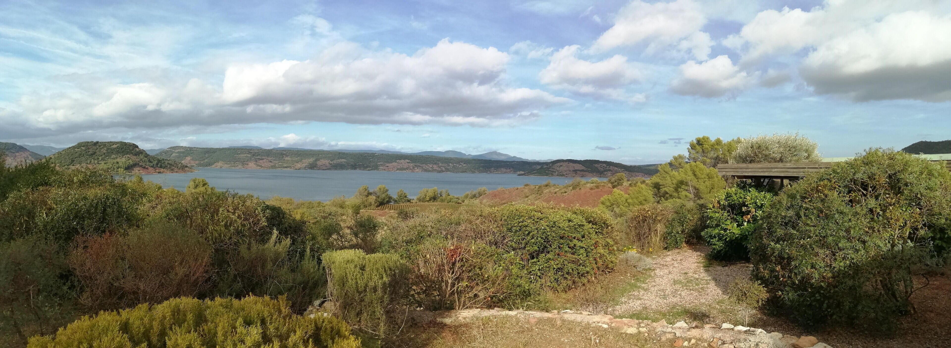 A natural landscape with a lake, hills, and a wooden structure.