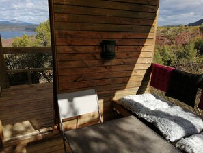 Um deck de madeira com um banco e uma mesa, com vista para uma paisagem deslumbrante com árvores e uma montanha.