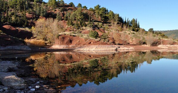 Um rio calmo refletindo árvores e terreno rochoso.