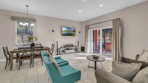 A modern living room with a dining area, a large window, and a view of the outdoors. - Comfortable 4br w/ private jacuzzi (Kissimmee)