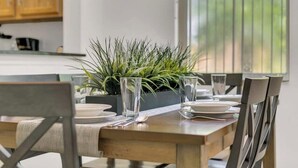 A dining table set with plates, glasses, and cutlery, flanked by chairs, with a potted plant in the center. - Comfortable 4br w/ private jacuzzi (Kissimmee)