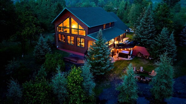 A cabin with a large deck and hot tub, surrounded by dense forest. - Big Bear Lodge Retreat where friends & families gather and meet! (Comins)