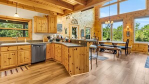 A spacious kitchen with wooden cabinets, a dishwasher, and a large island with bar stools. - Big Bear Lodge Retreat where friends & families gather and meet! (Comins)